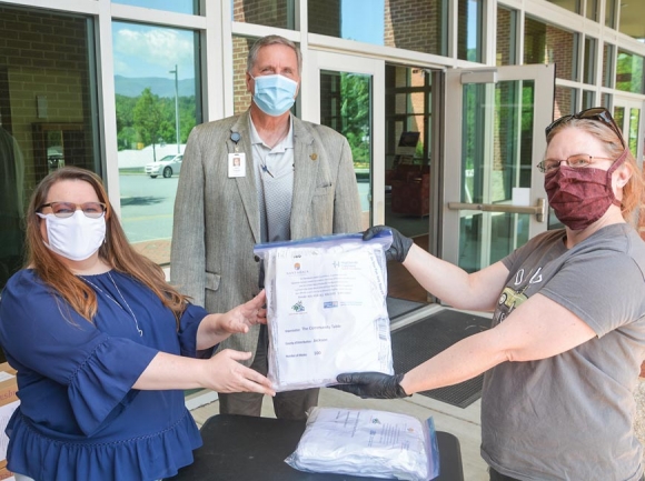 Lori Bailey, executive director of the Nantahala Health Foundation, (from left) poses with a package of masks alongside SCC President Dr. Don Tomas and Paige Christie, director of The Community Table in Sylva.