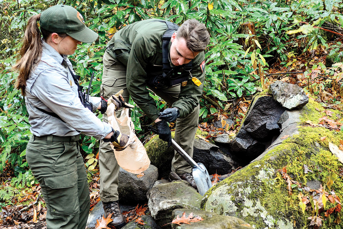 Backcountry rangers Lydia Williams (left) and Jordan Gibeault dismantle an illegal campfire ring near Kephart Prong Shelter. 